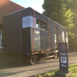 Ein Tiny House wir auf einen Traktor-Anhänger transportiert.