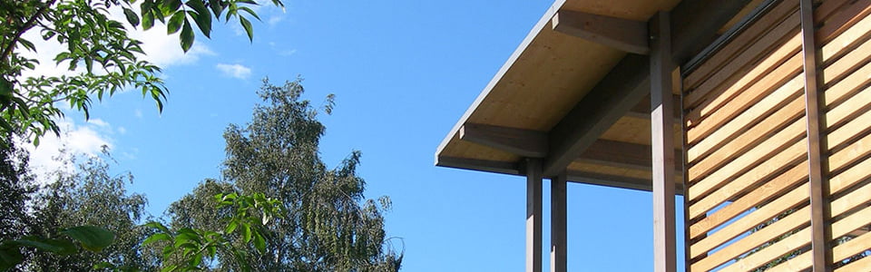 Stimmungsvoller Blick in den blauen Himmel nebst Hausfassade und Bäumen.