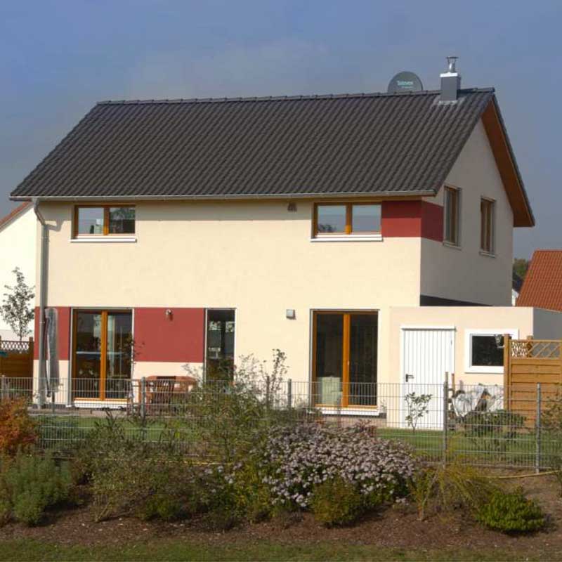 Rückansicht auf das Einfamilienhaus Effi 55 mit Garten und angrenzender Garage.