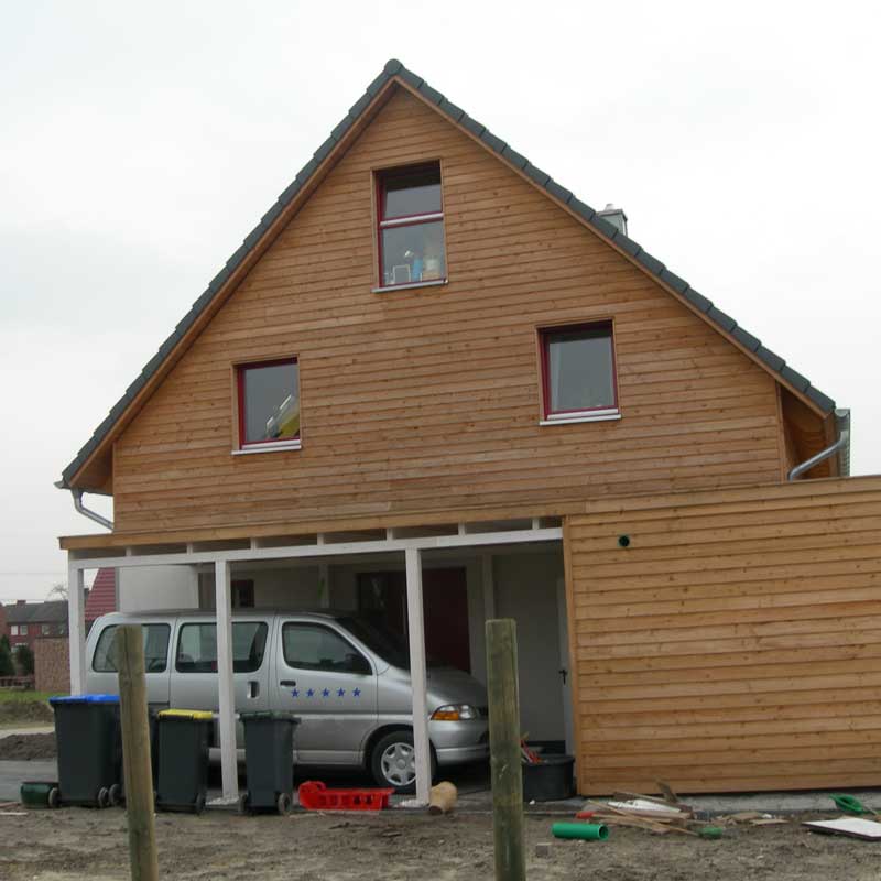 Seitenansicht auf das Carport des Doppelhauses, unter dem ein silberner PKW geparkt wurde.