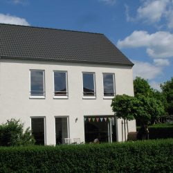 Ein charmantes Einfamilienhaus KFW 60 von Wohnbehagen, mit vielen Fenstern und einer weißen Fassade.