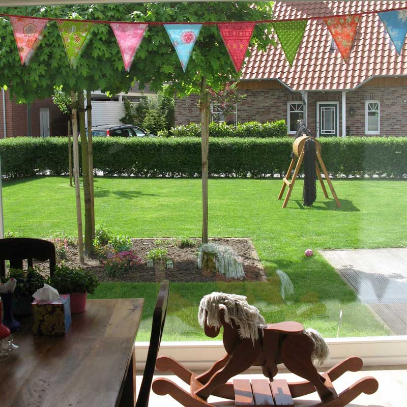 Großes und tiefes Fenster mit Blick in den Garten und einem davor platzierten Schaukelpferd.