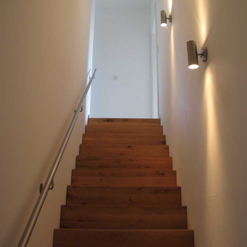 Treppenaufgang mit stimmungsvoller Wandbeleuchtung.