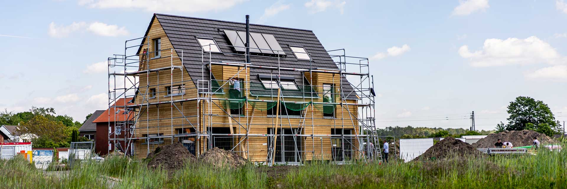 Ein noch nicht ganz fertiges Holzhaus mit Baustellengerüst.