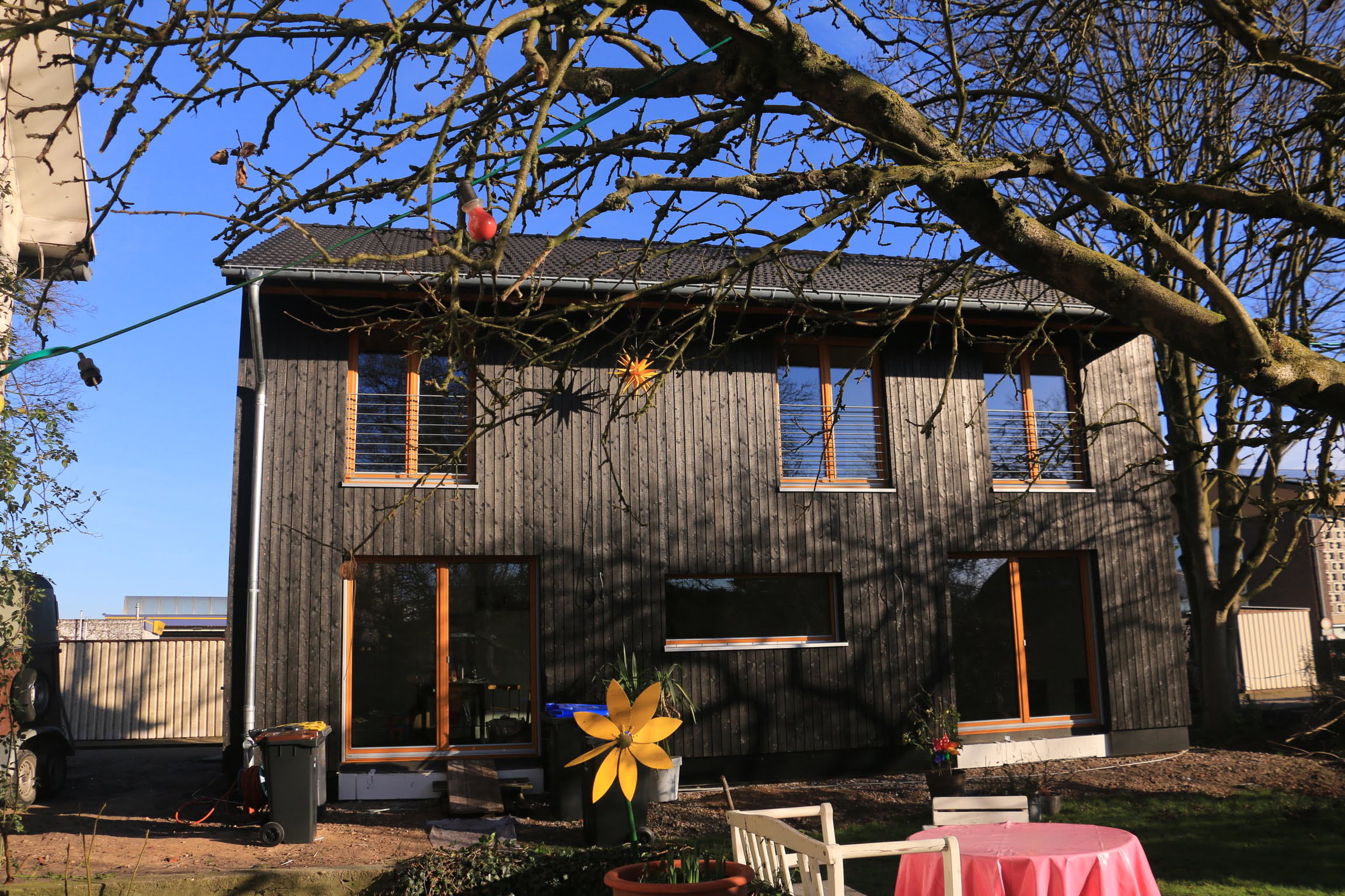 Ein Holzhaus von Wohnbehagen mit dunkelgrauer Holzvertäfelung an der Außenwand.