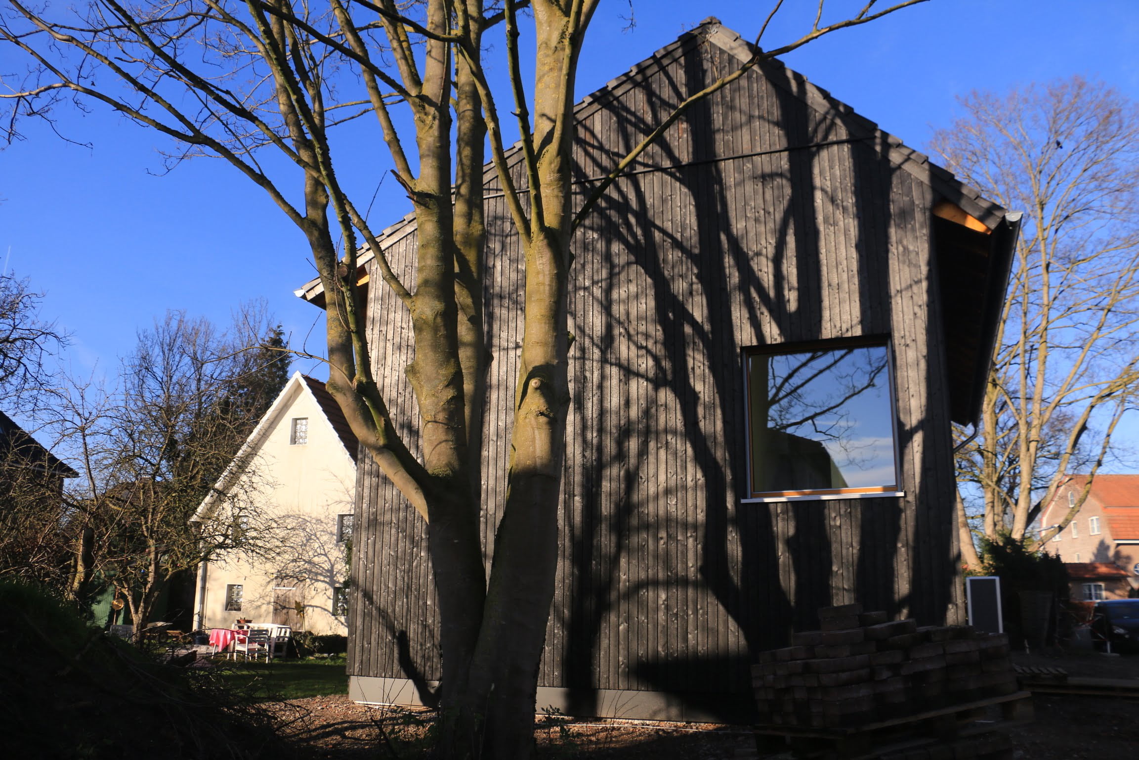 Stirnseite von einem Holzhaus von Wohnbehagen mit einem großen quadratischen Fenster.