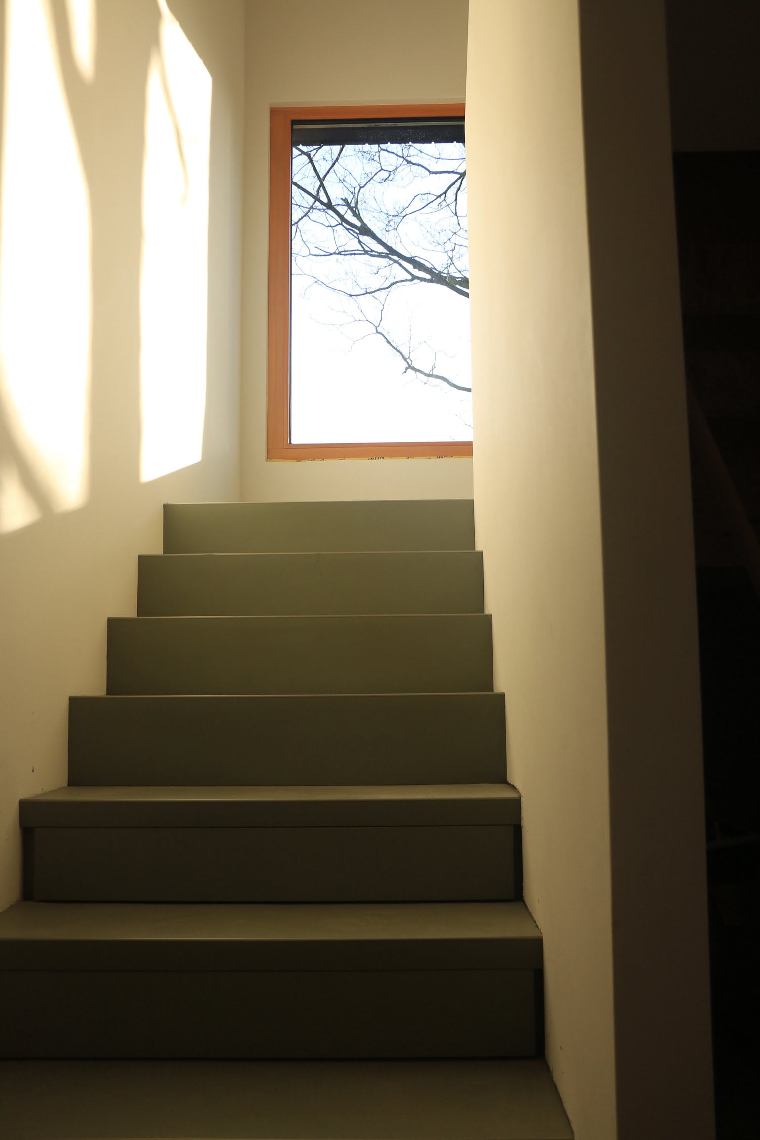 Treppenaufstieg mit einem großen Fenster führt in das Obergeschoss des Holzhauses von Wohnbehagen.