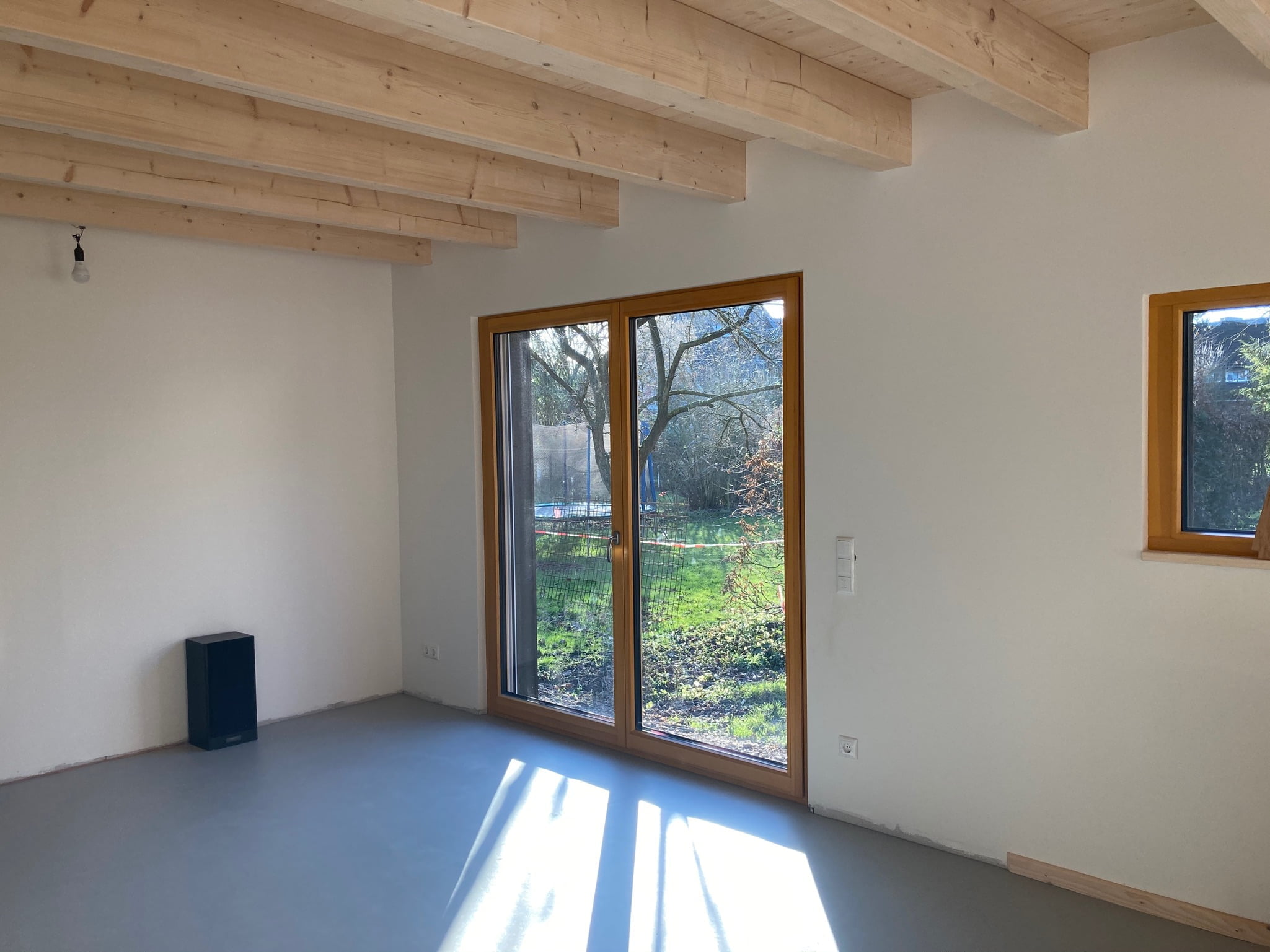 Inneneinsicht in den Wohnraum eines Holzhauses von Wohnbehagen mit bodentiefen Fenstern.
