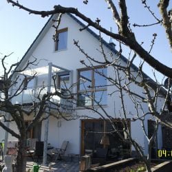 Blick aus dem Garten auf den verputzten Anbau an ein Familienhaus von Wohnbehagen.