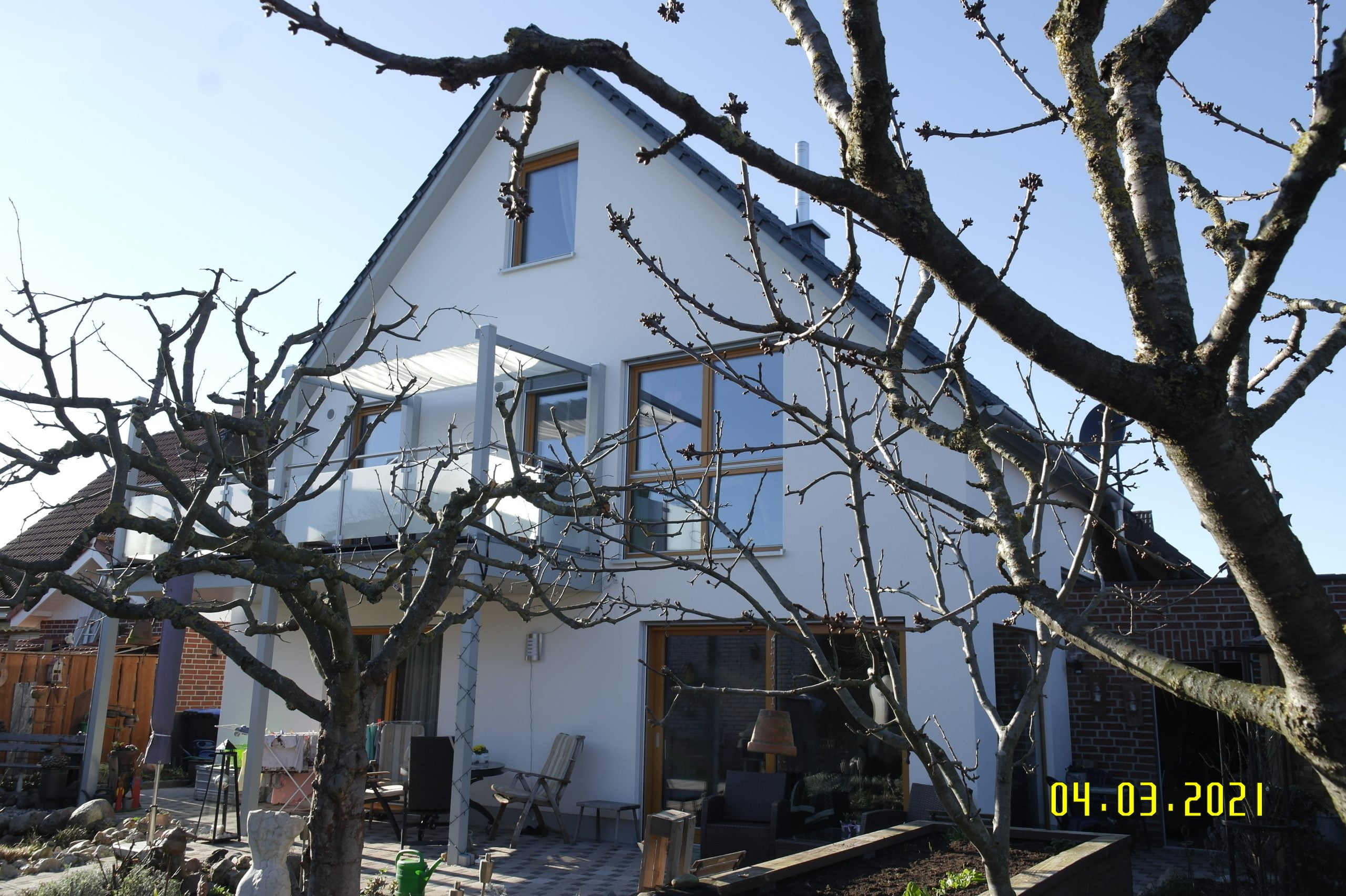 Blick aus dem Garten auf den verputzten Anbau an ein Familienhaus von Wohnbehagen.