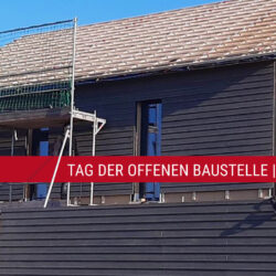 Ein unfertiges Holzfertighaus mit Baugerüsten lädt zum Tag der offenen Baustelle ein.